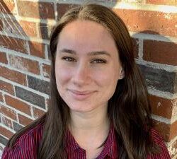 A young white woman with long straight brown hair smiles