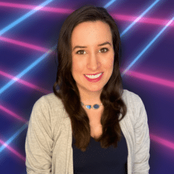 A young white woman with medium-length dark hair and a teal necklace smiles broadly