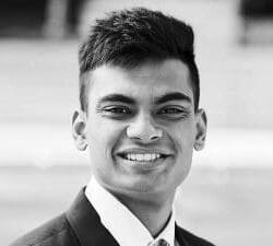 Rishab Datta; a black and white photo of a young man with dark hair, smiling and wearing a suit